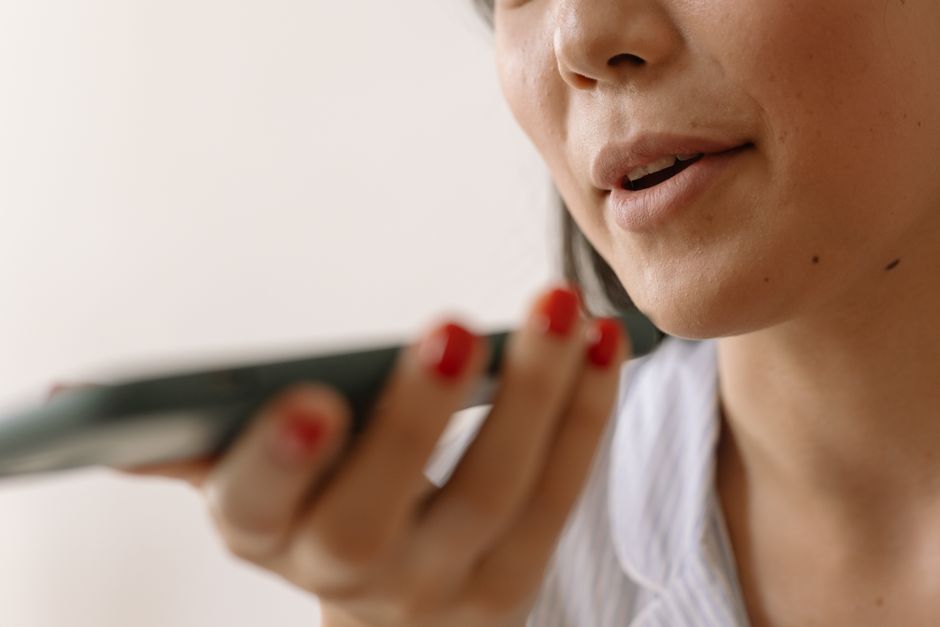 person speaking into smartphone, voice assistant sound waves, hands-free mobile working