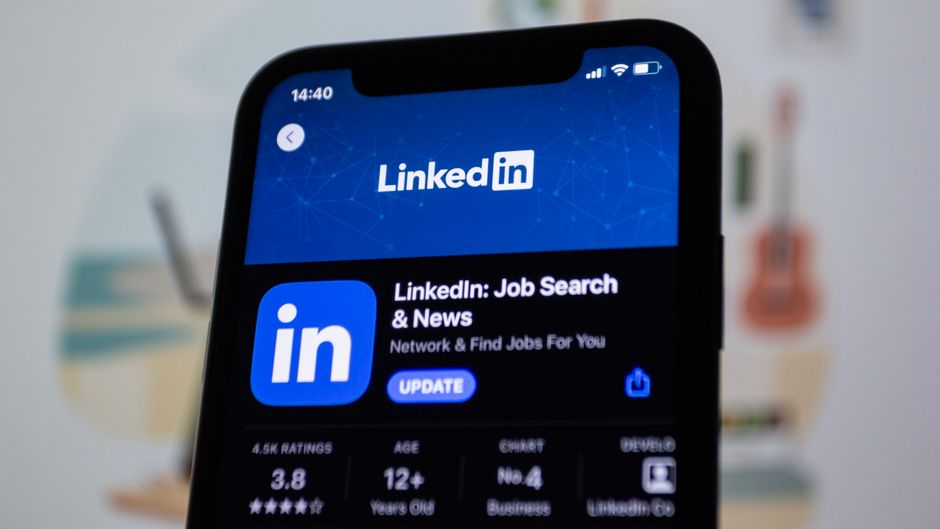 LinkedIn app smartphone screen, office worker laptop feed, report button interface