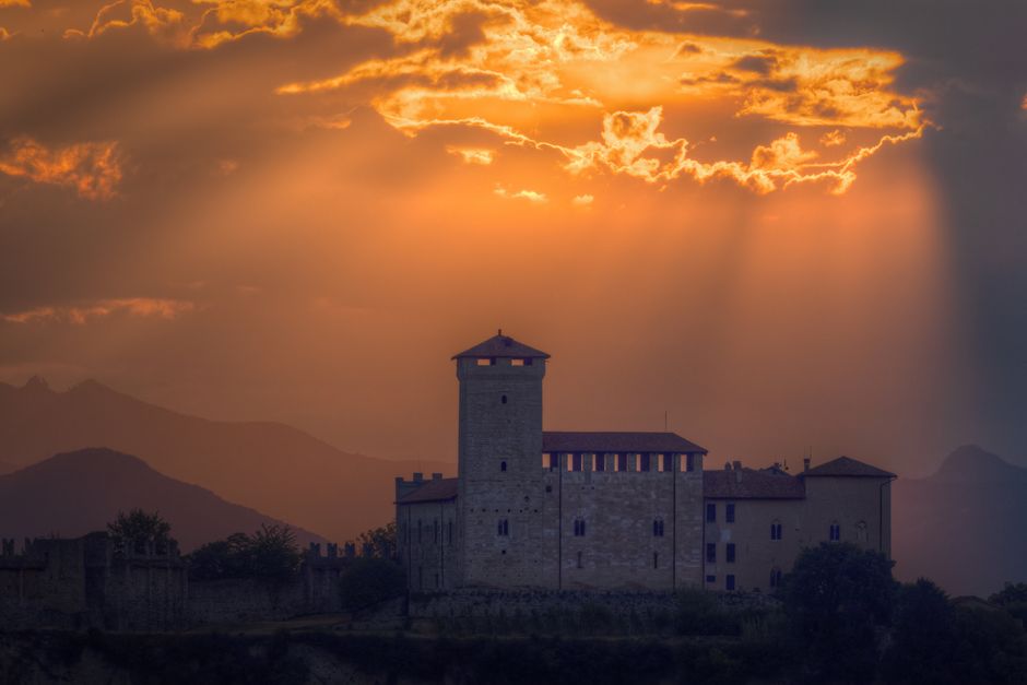 dragon silhouette flying, medieval castle at dusk, burning castle