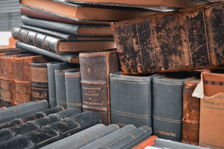 stacked old books spines, warehouse conveyor boxes, book scanner