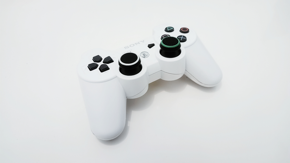 PlayStation 3 console, retro video game controller, stack of game discs